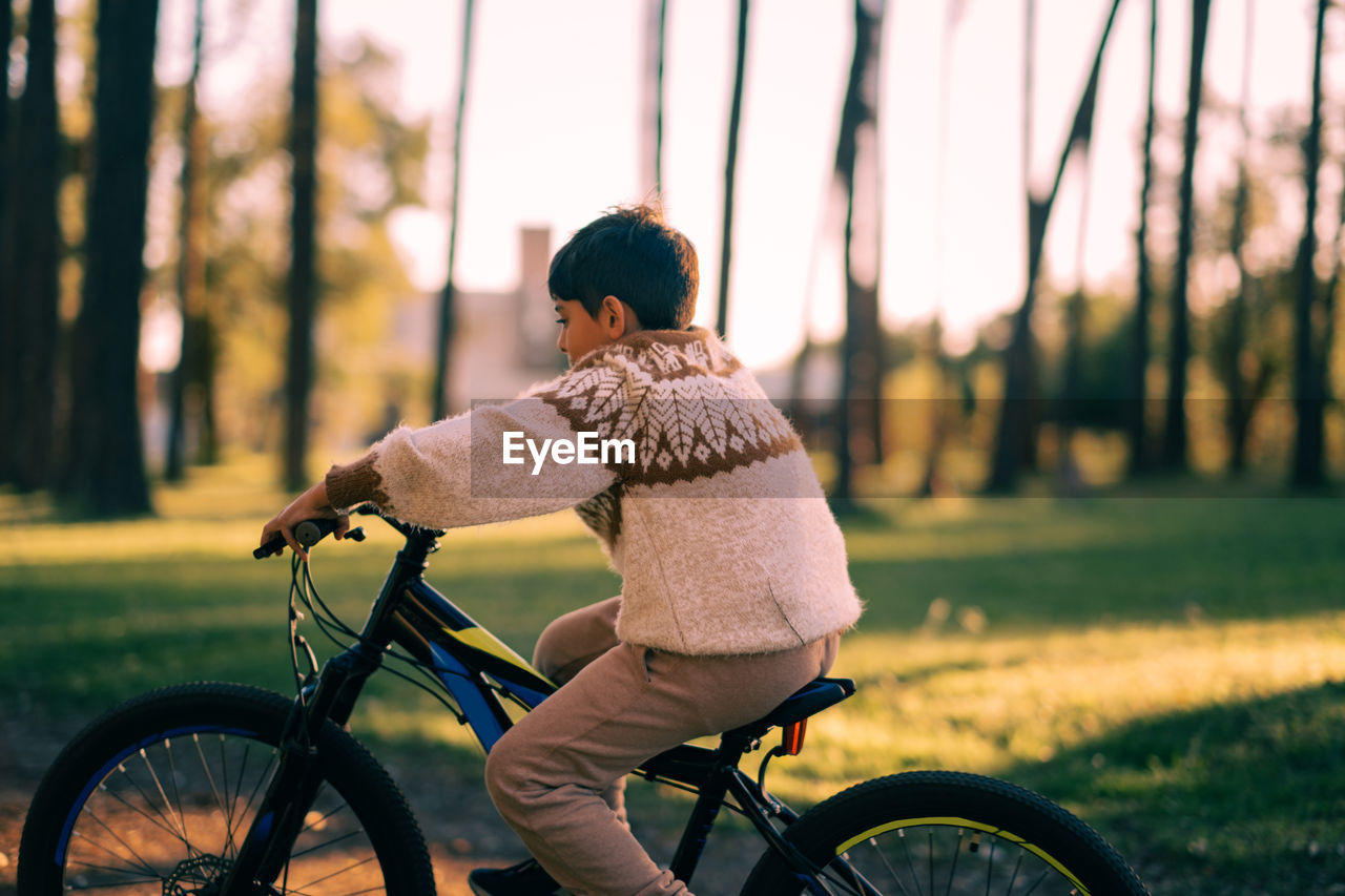 Side view of boy riding bicycle at park