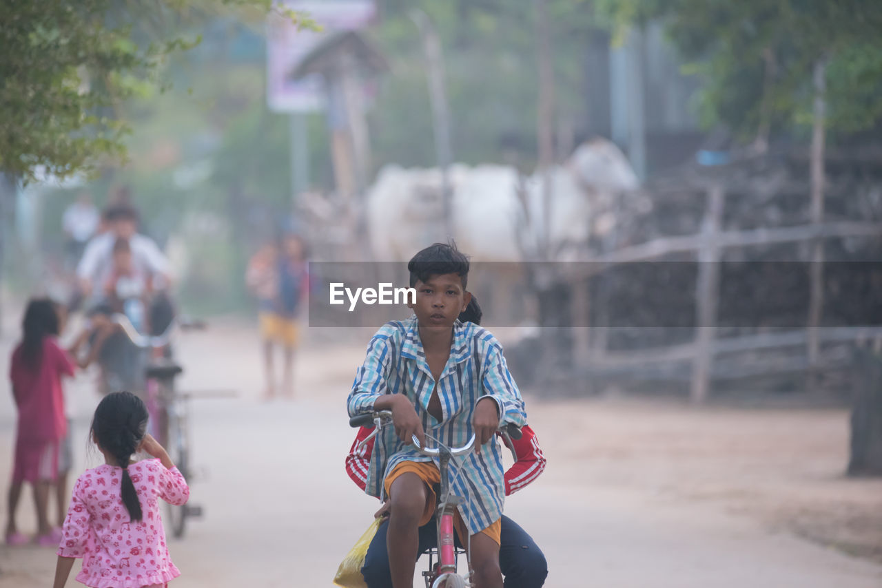 REAR VIEW OF PEOPLE RIDING GIRL ON MOTORCYCLE