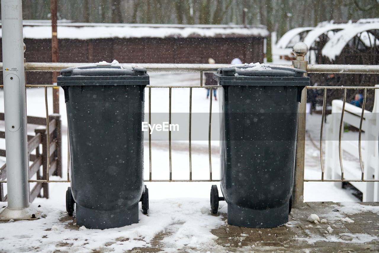 Grey garbage bins on street in winter. public trash containers on side of road. infectious control