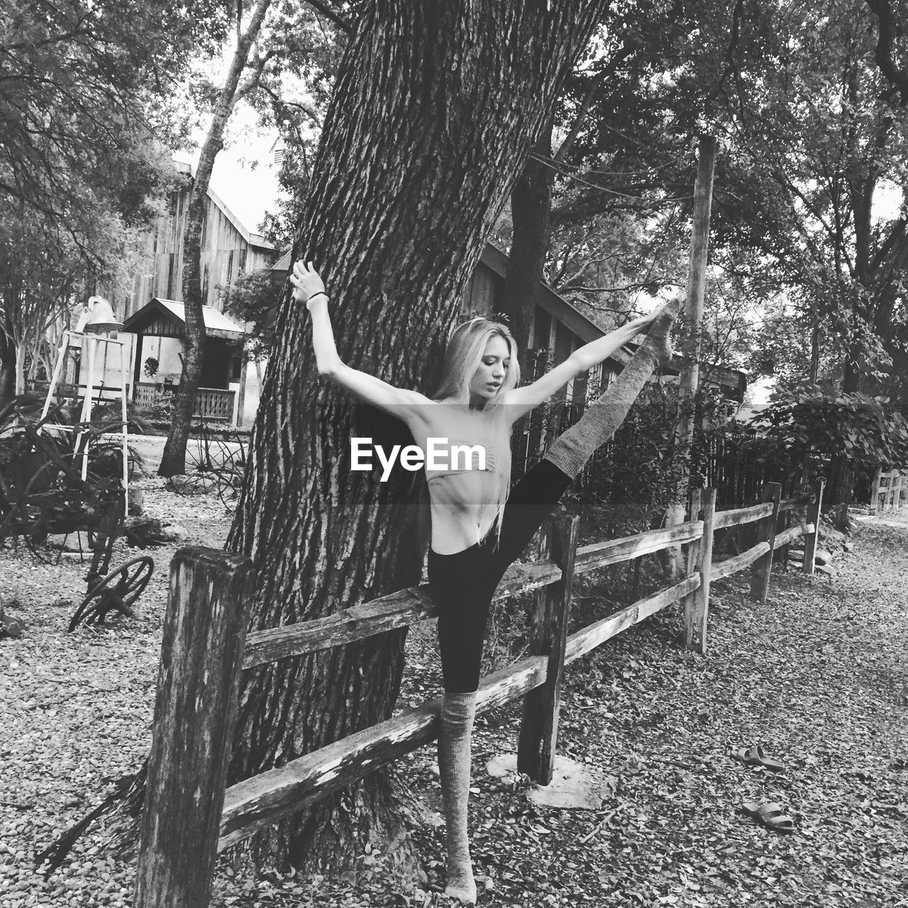 Woman performing yoga by tree on field