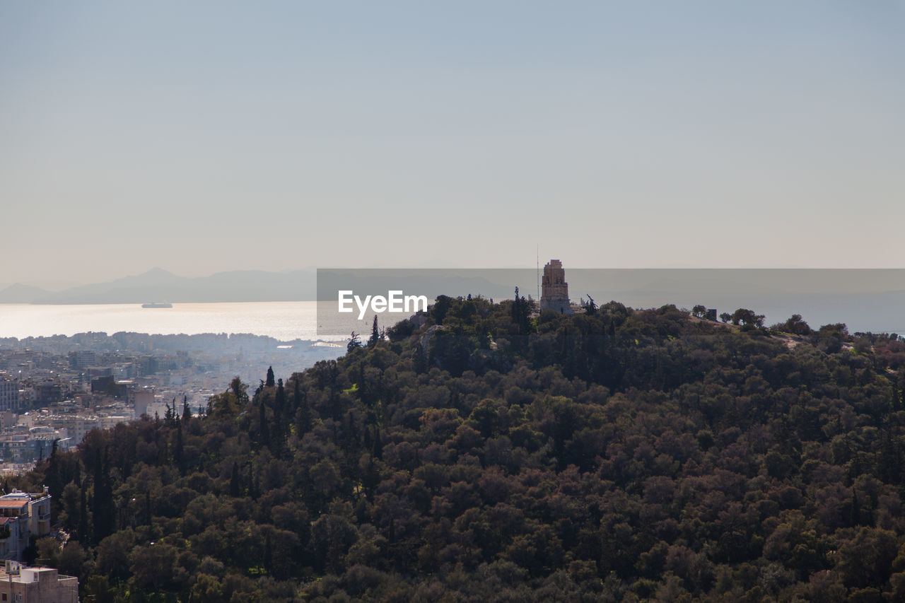 Cityscape by sea against clear sky