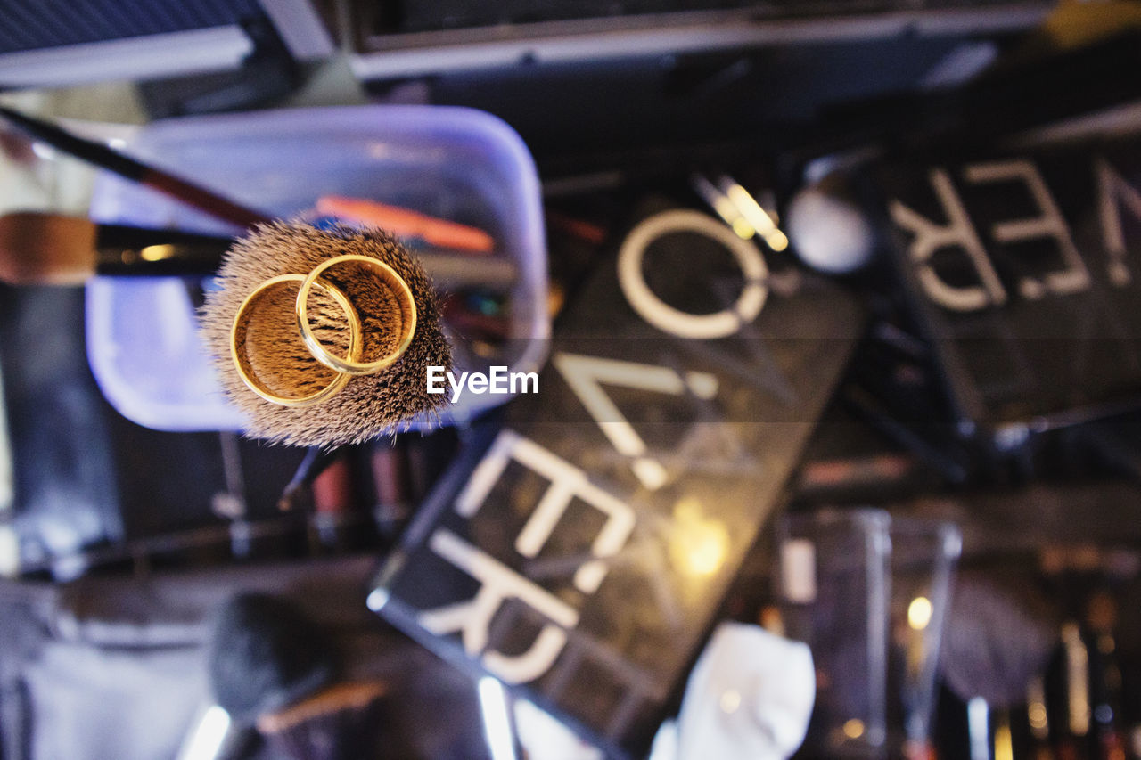 Directly above shot of wedding rings on make-up brush at table