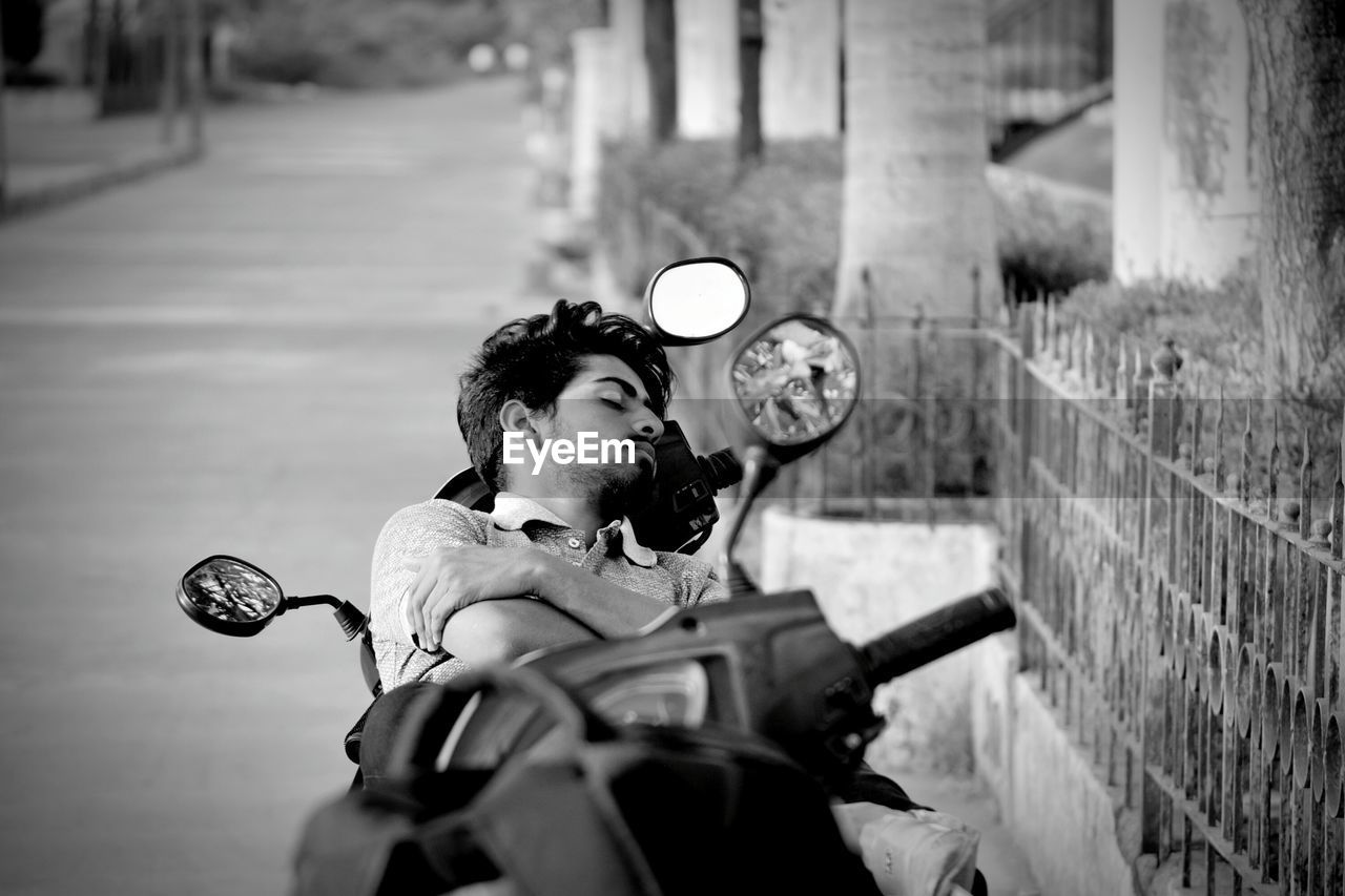 High angle view of young man sleeping on motor scooter