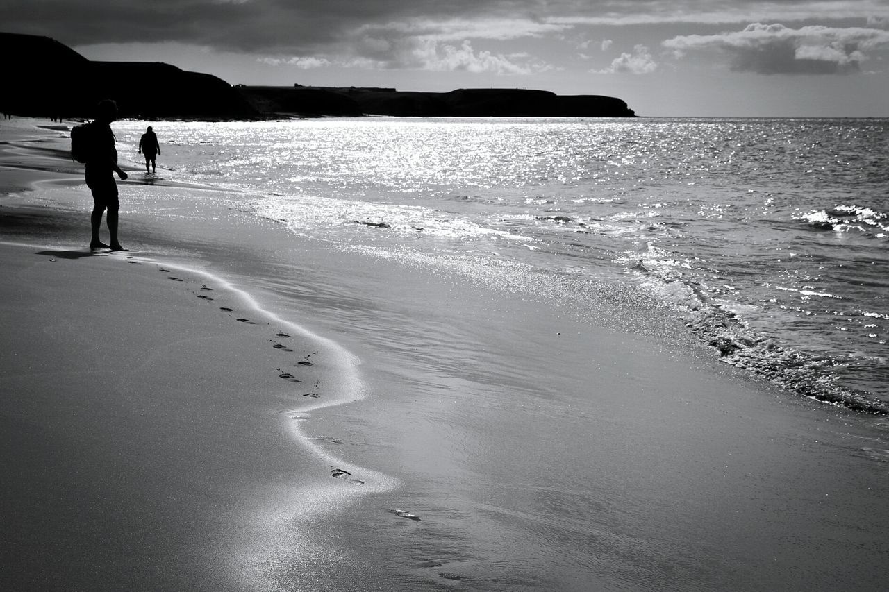 FULL LENGTH OF WOMAN WALKING ON BEACH AGAINST SKY