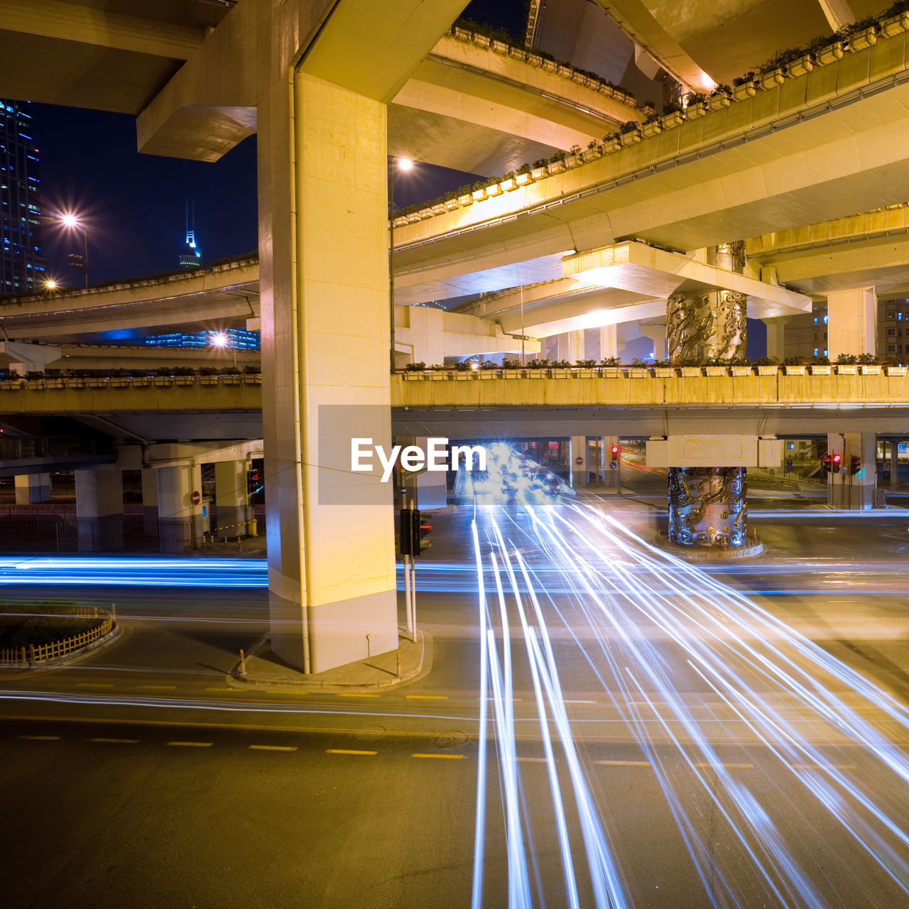 LIGHT TRAILS ON BRIDGE OVER ROAD AT NIGHT