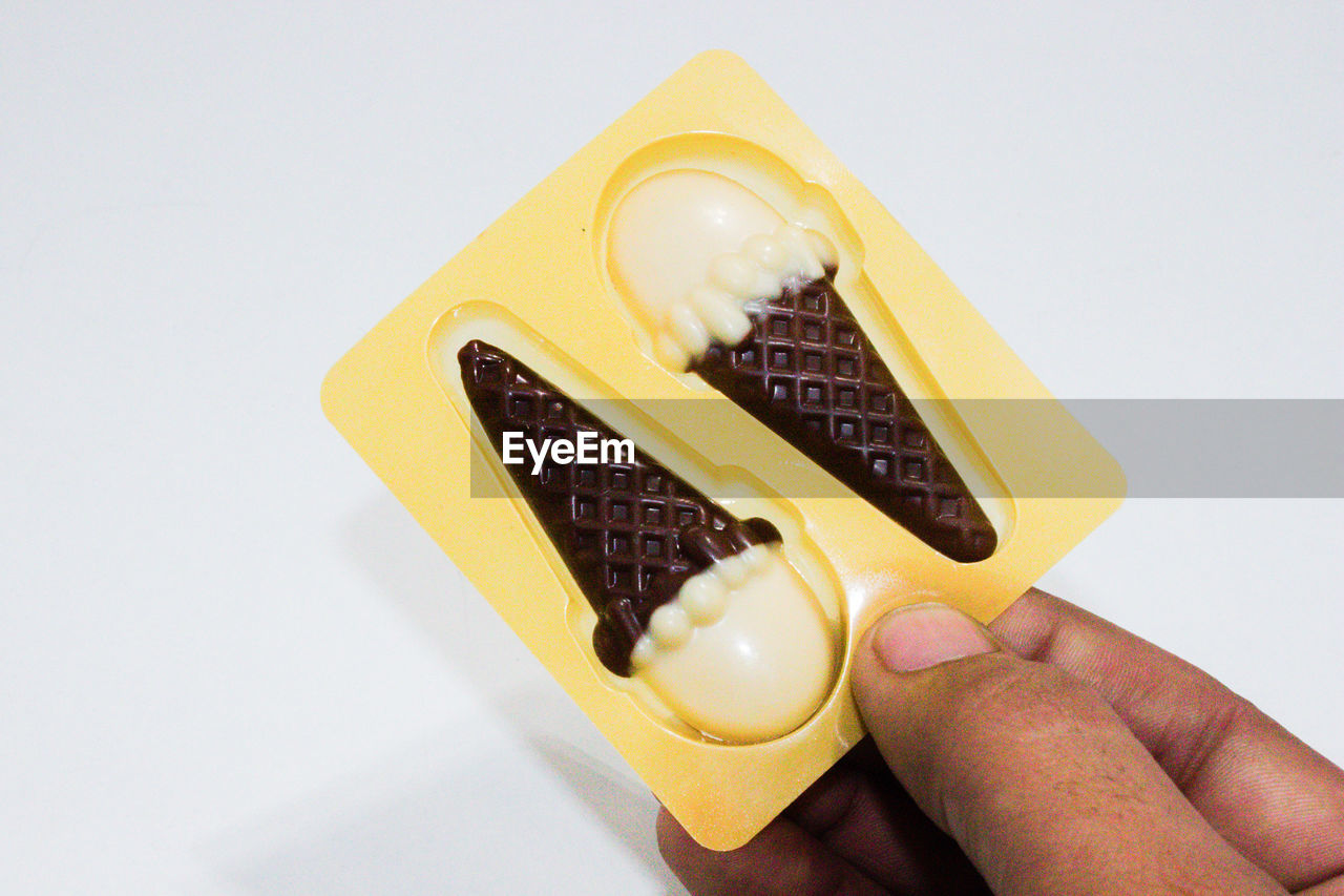 CLOSE-UP OF HAND HOLDING ICE CREAM CONE