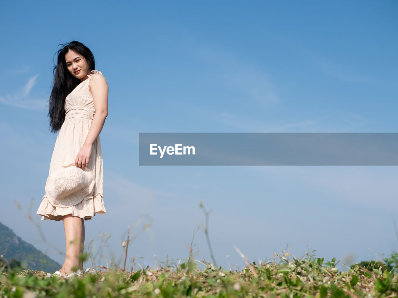 Portrait of young woman standing against sky