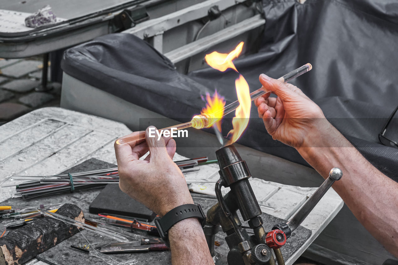 HIGH ANGLE VIEW OF MAN HOLDING FIRE ON BARBECUE