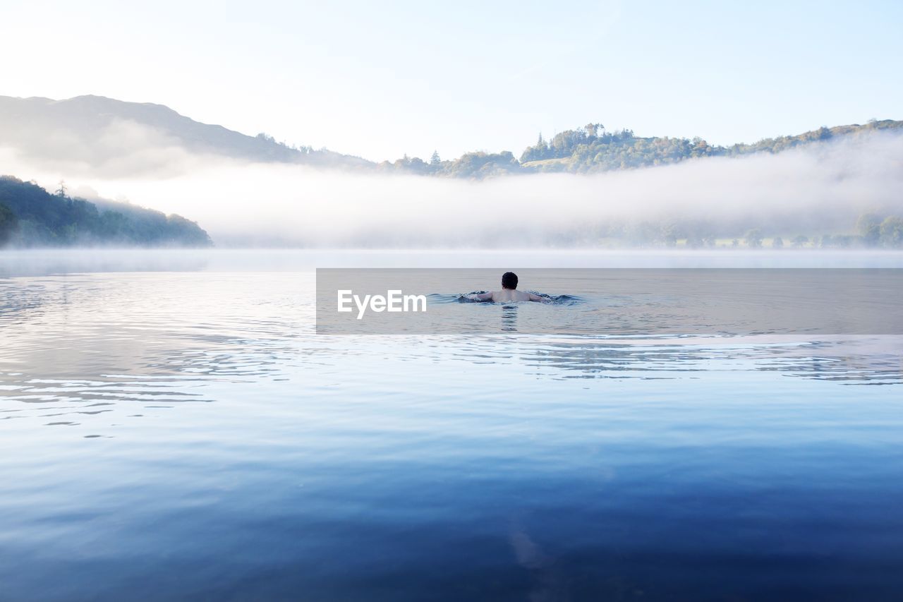 Rear view of man swimming in lake