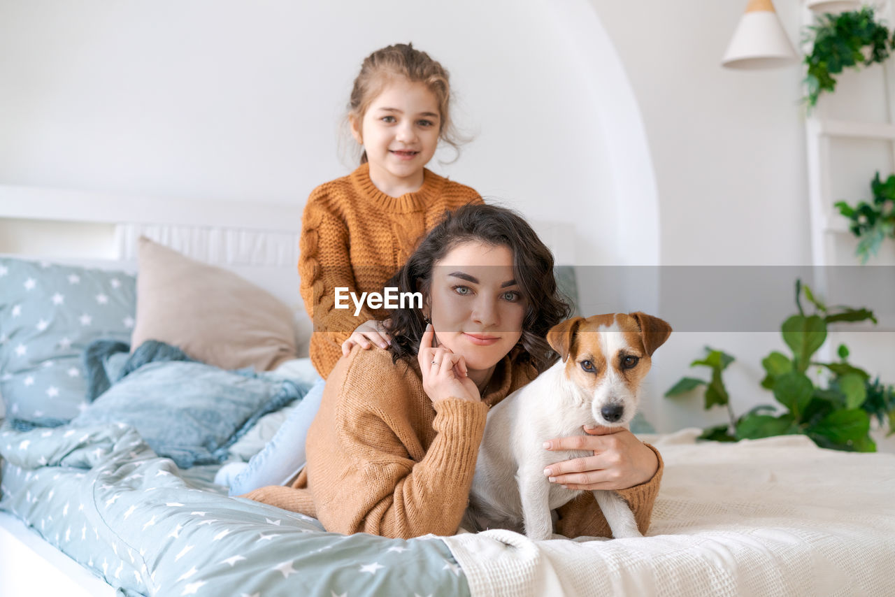 Happy mom and daughter play with their adorable wired jack russell terrier