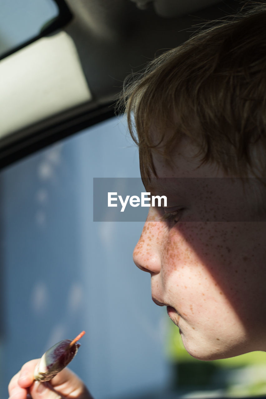 Close-up of boy having food while sitting in car