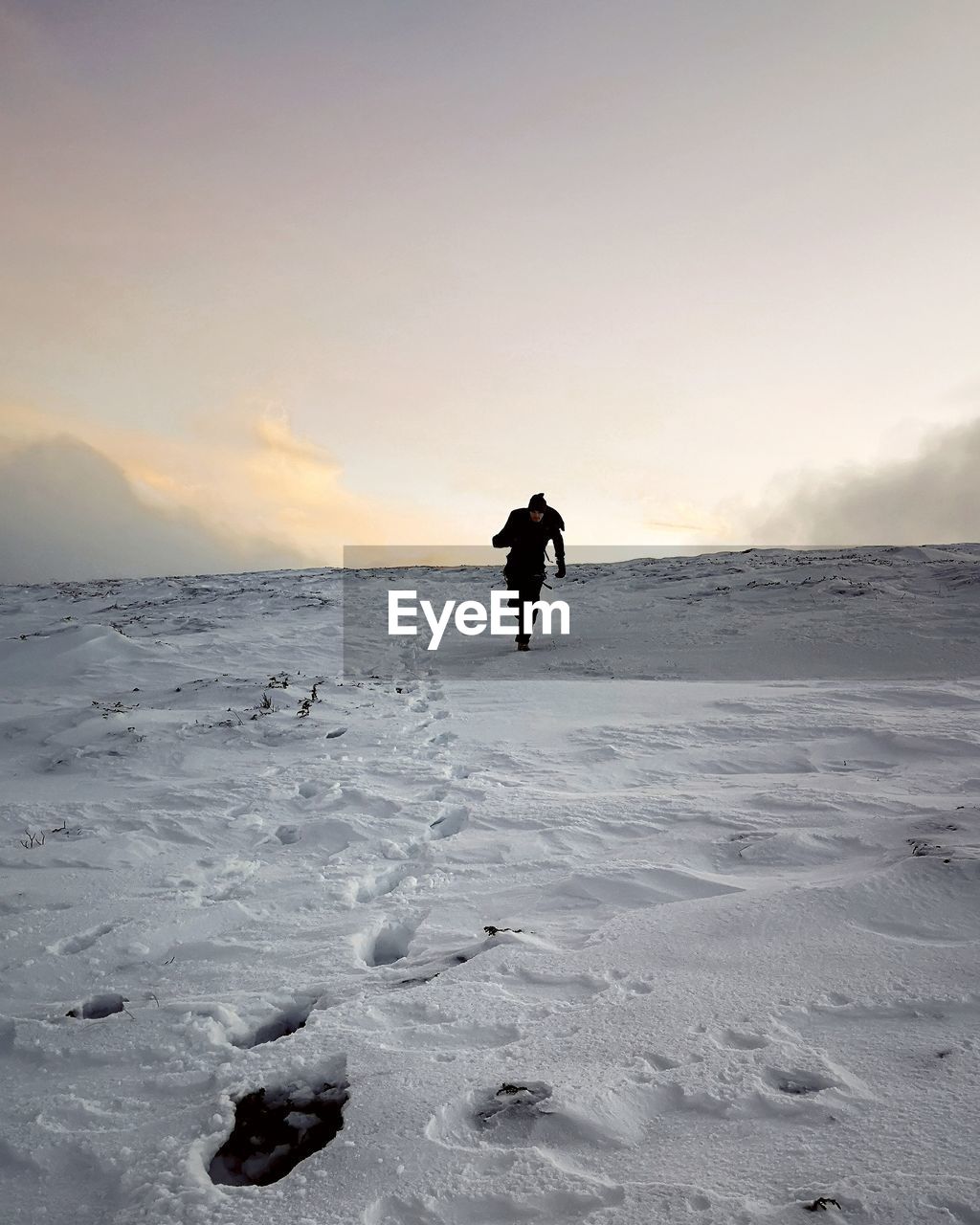 Man walking on snow during sunset