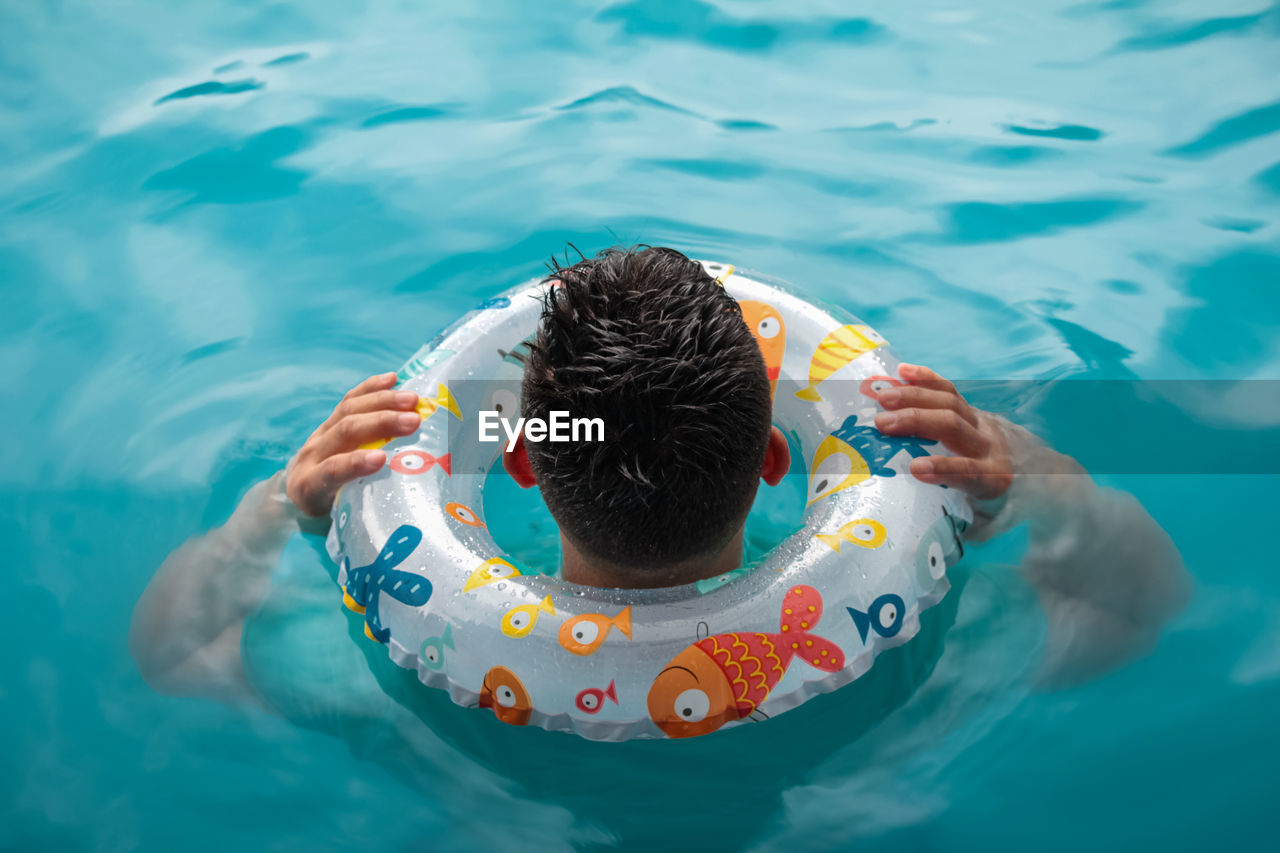 High angle view of man swimming in pool with inflatable 