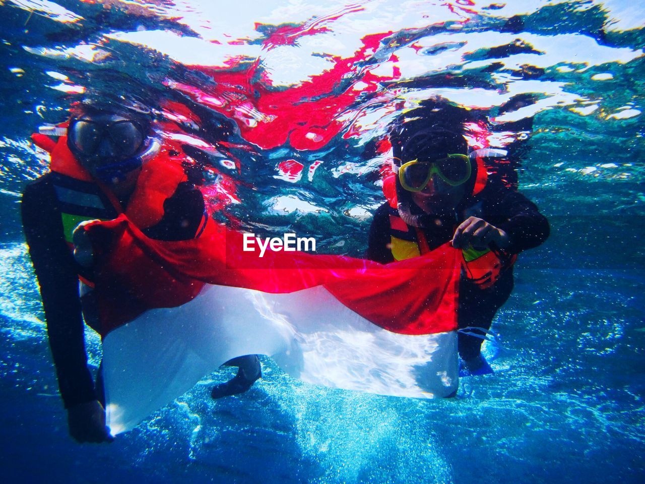 Scuba divers with indonesian flag in sea