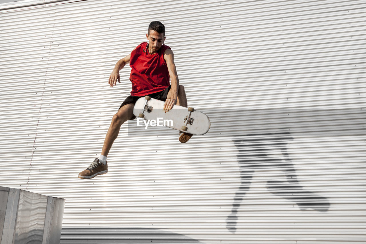 Man with skateboard in mid-air against wall
