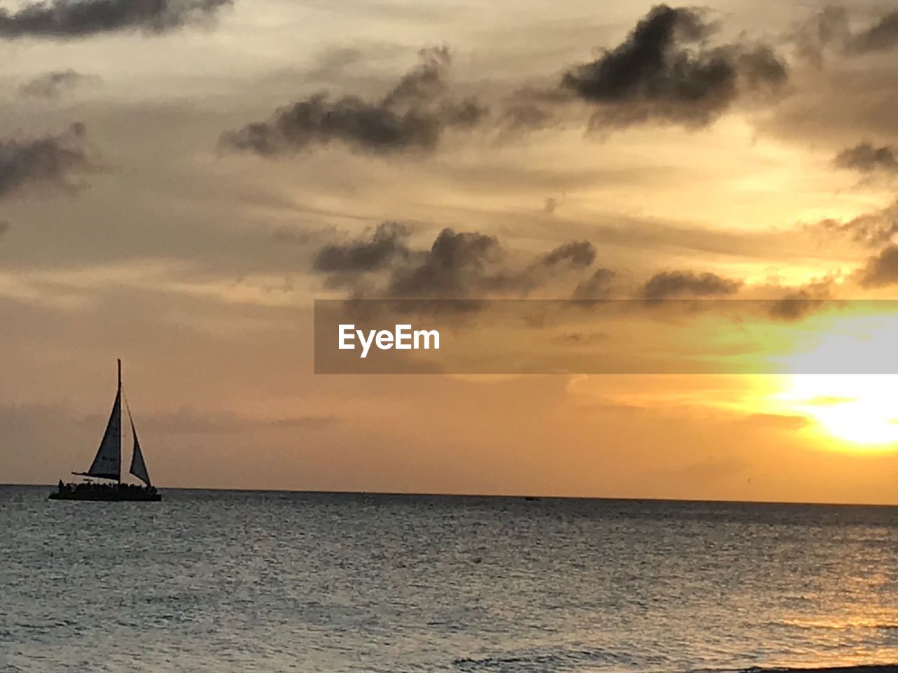 SAILBOAT SAILING IN SEA AGAINST SKY DURING SUNSET