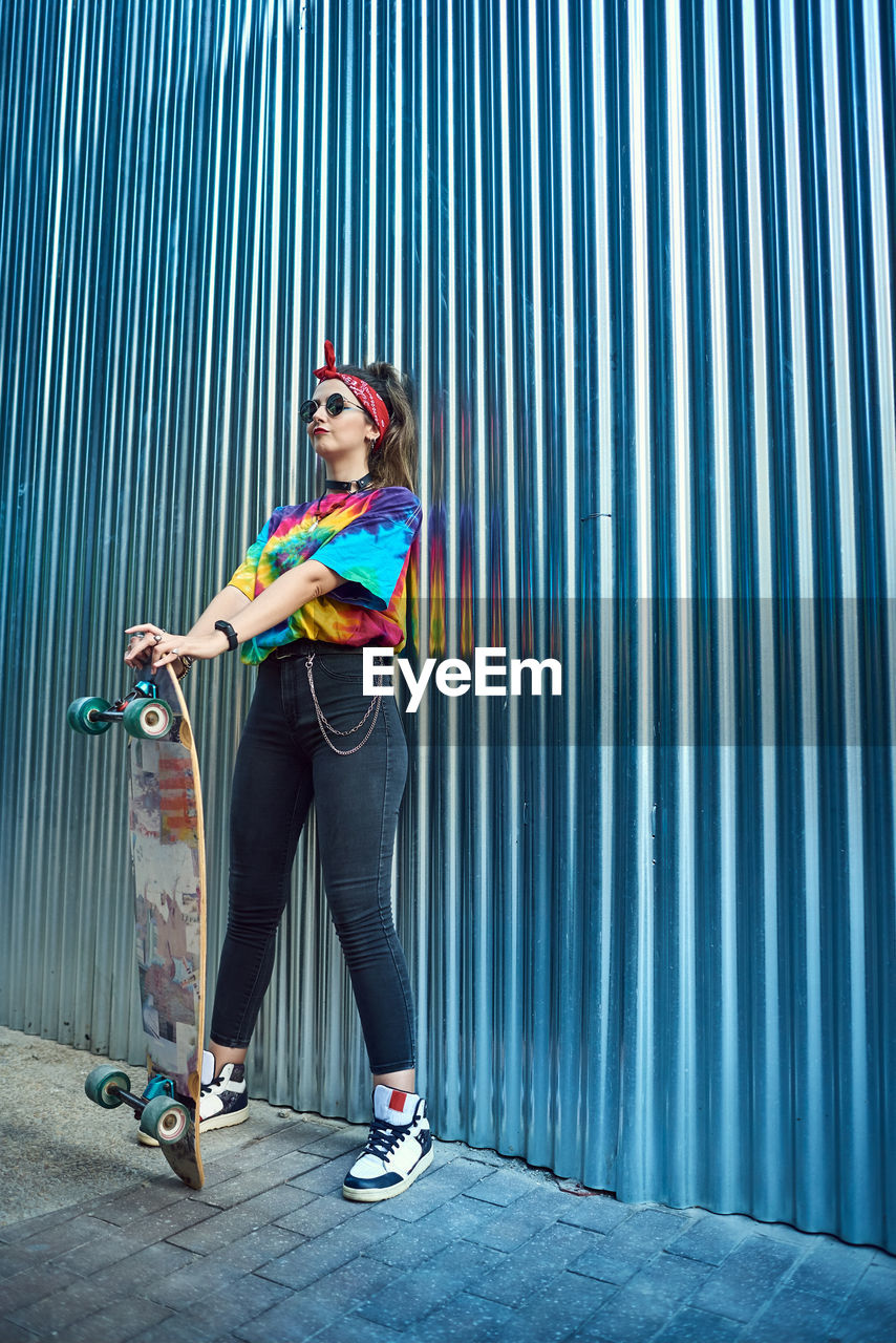 Young woman with urban style, she poses with a long board.