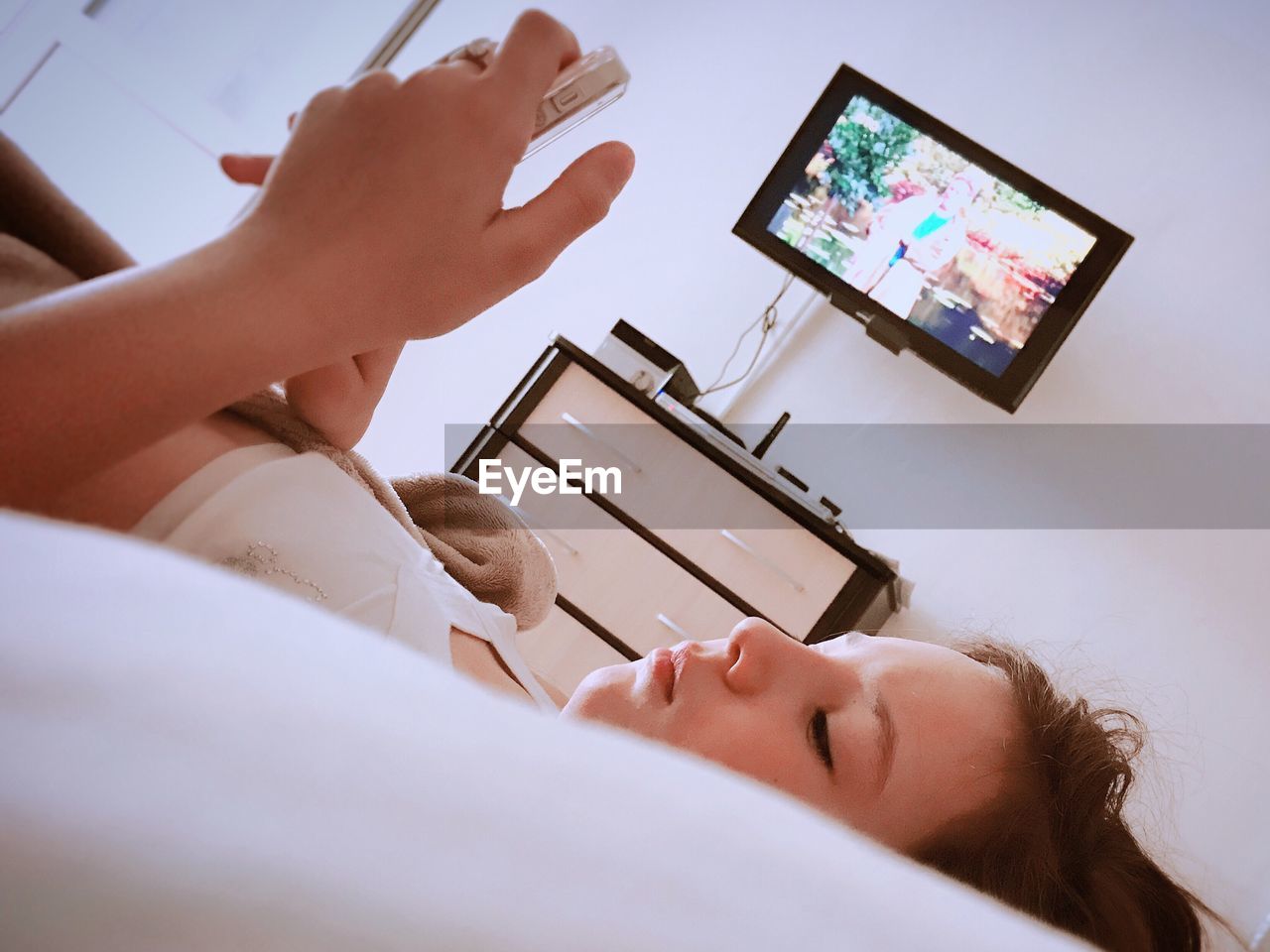 Girl using mobile phone while lying on bed at home