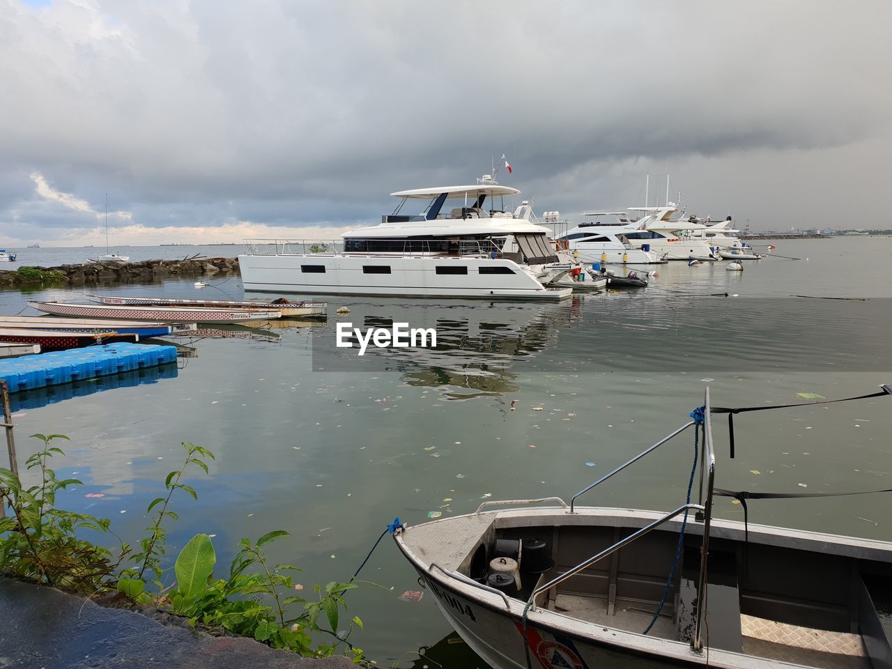 Fishing boats moored at harbor against sky