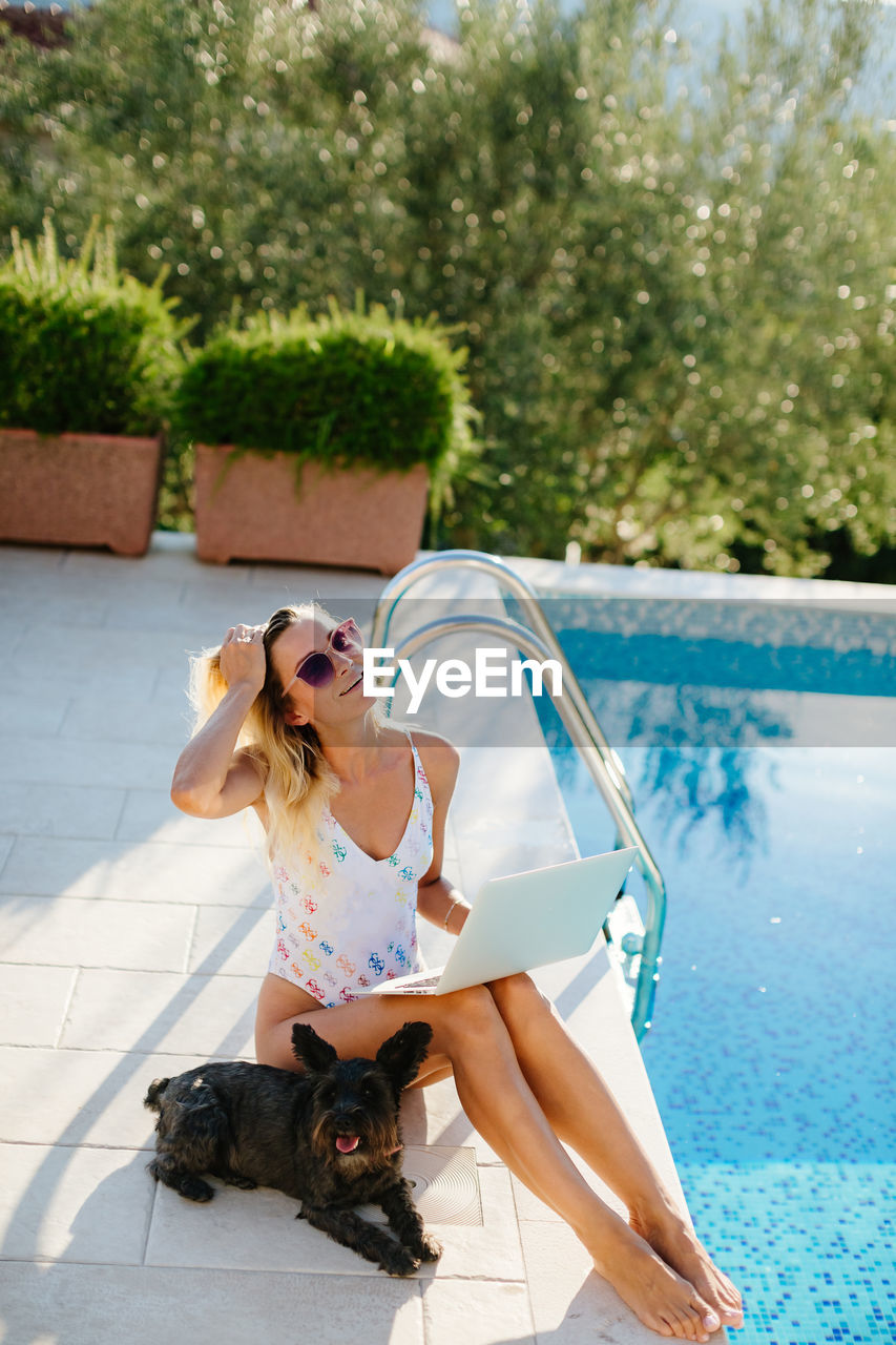 High angle view of woman using laptop by swimming pool