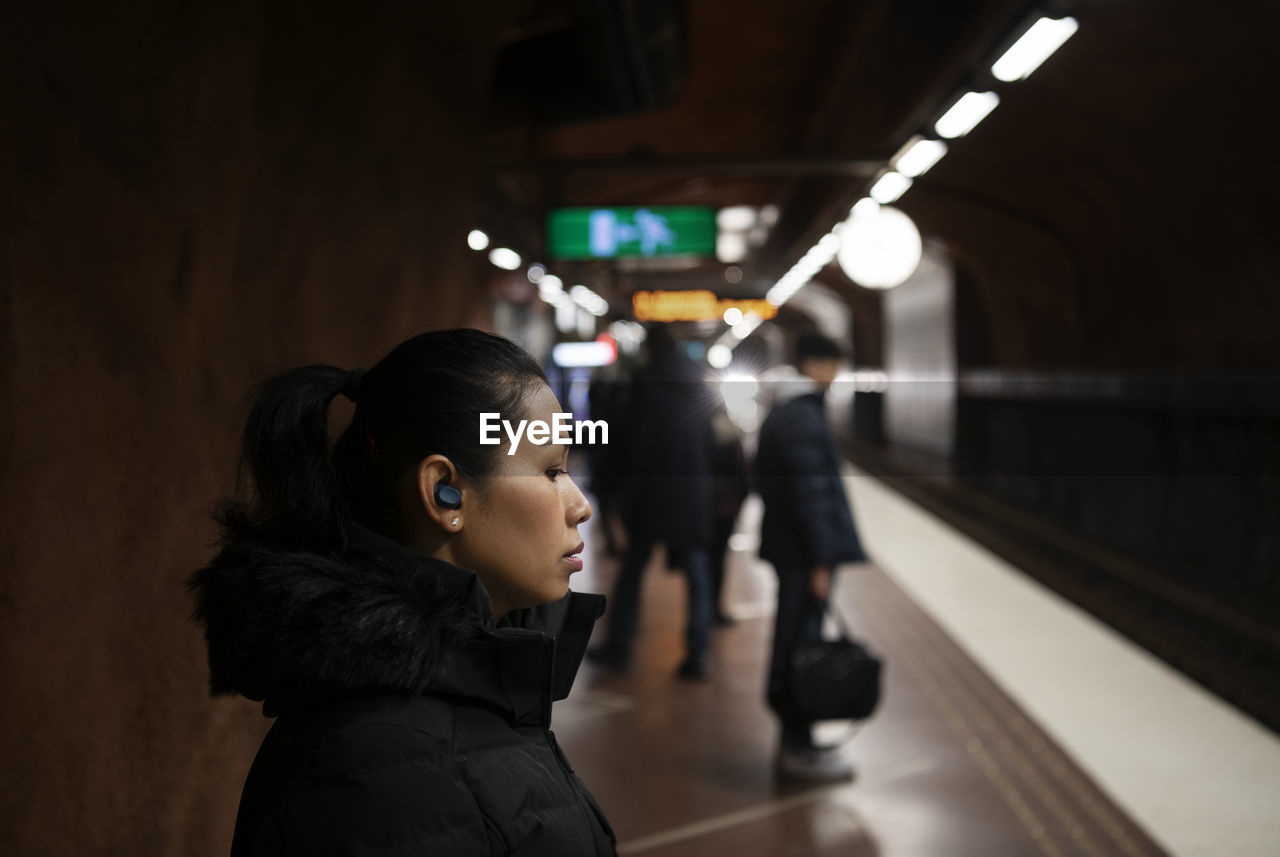 Woman with earphones standing at metro station