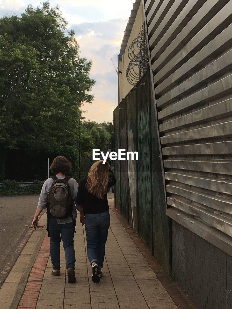 Rear view full length of sisters walking on sidewalk