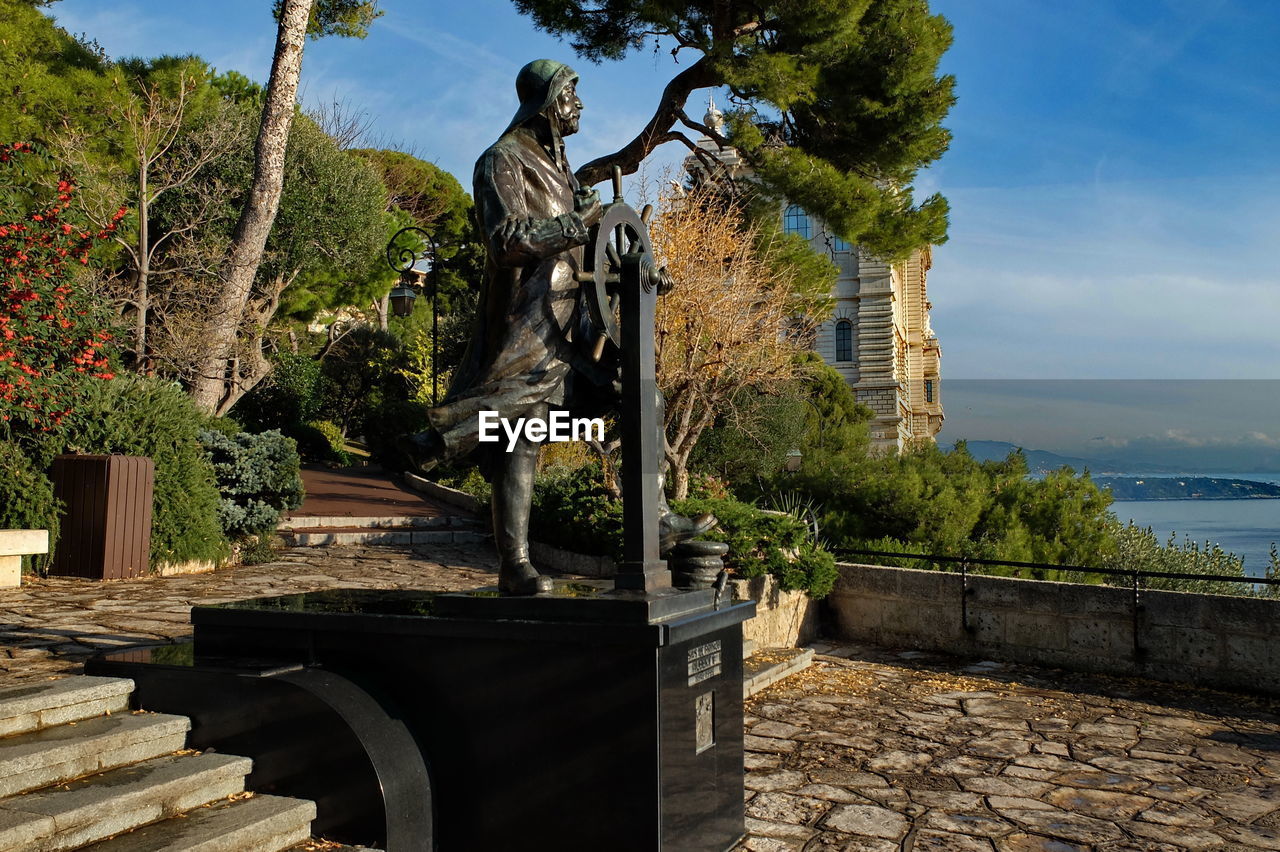 Statue by trees against sky