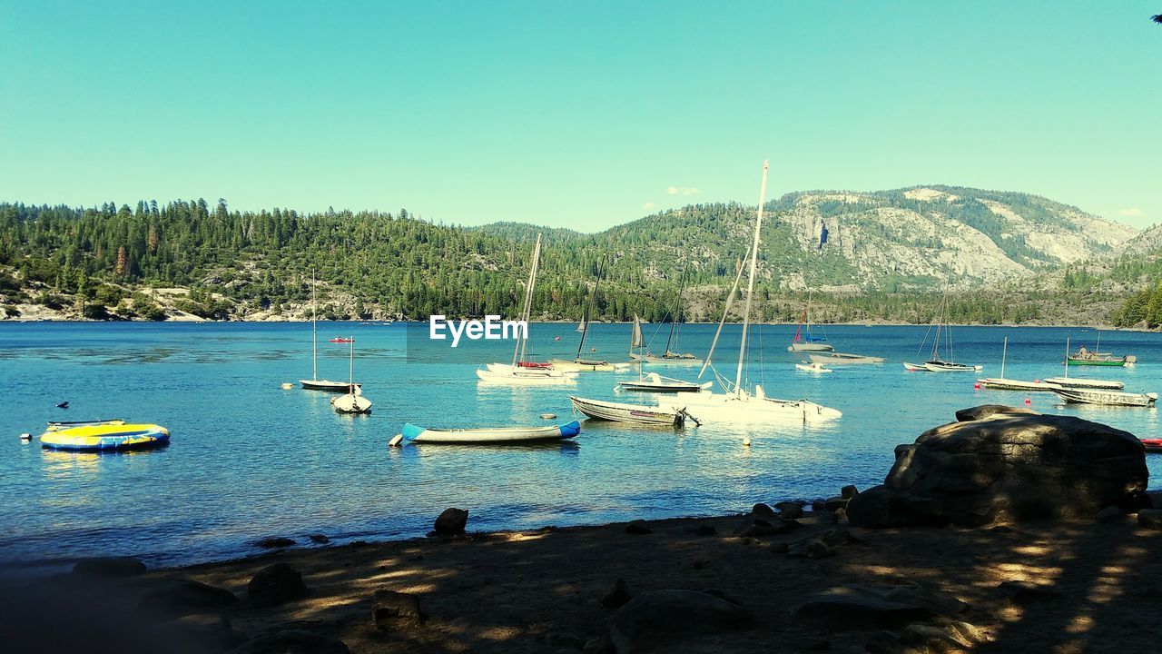 BOATS MOORED ON SEA AGAINST CLEAR SKY