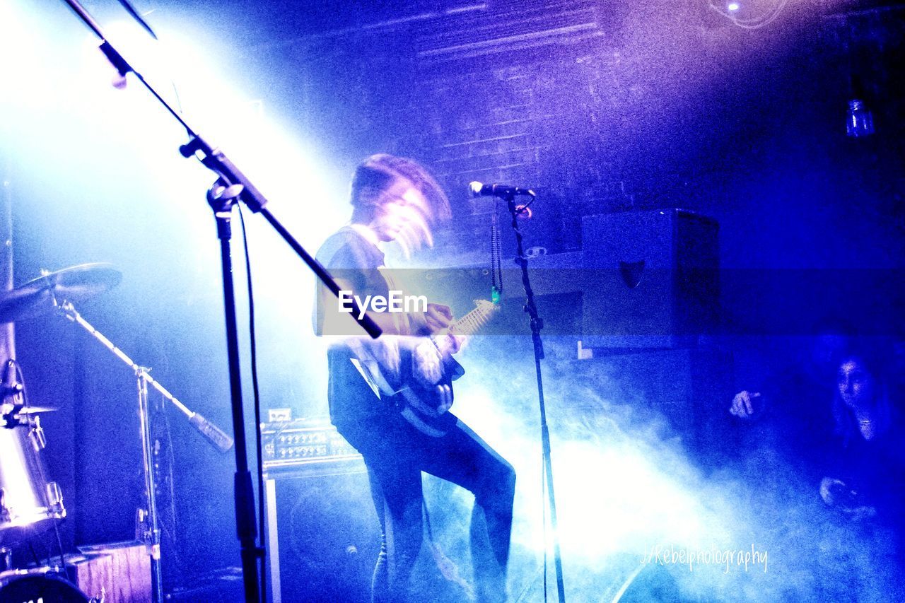 MAN PLAYING GUITAR AT CONCERT