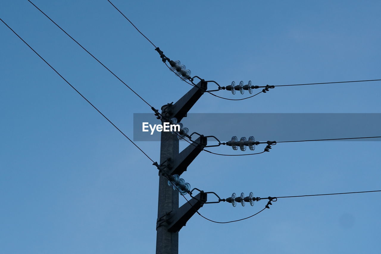 Low angle view of electricity pylon against clear sky