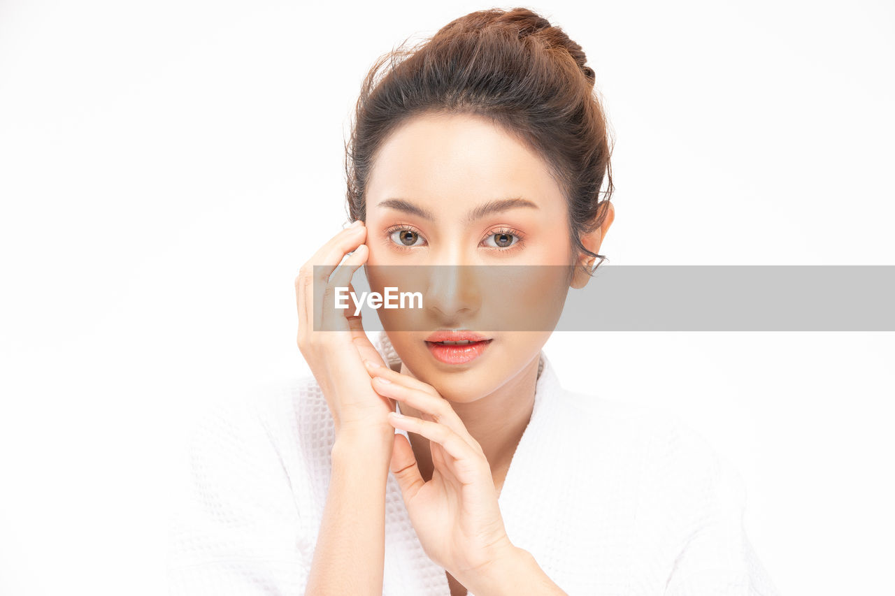 PORTRAIT OF BEAUTIFUL YOUNG WOMAN OVER WHITE BACKGROUND