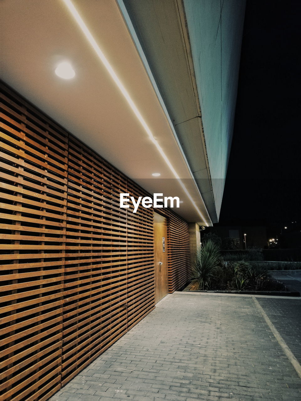 Illuminated empty parking lot by building at night