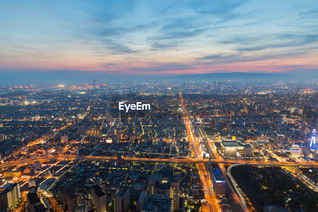 High angle view of illuminated city against sky during sunset