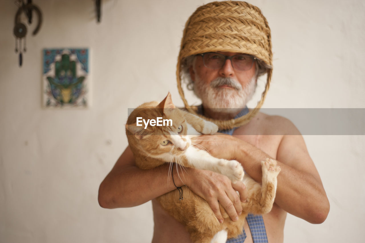 PORTRAIT OF A MAN WITH CAT IN BACKGROUND