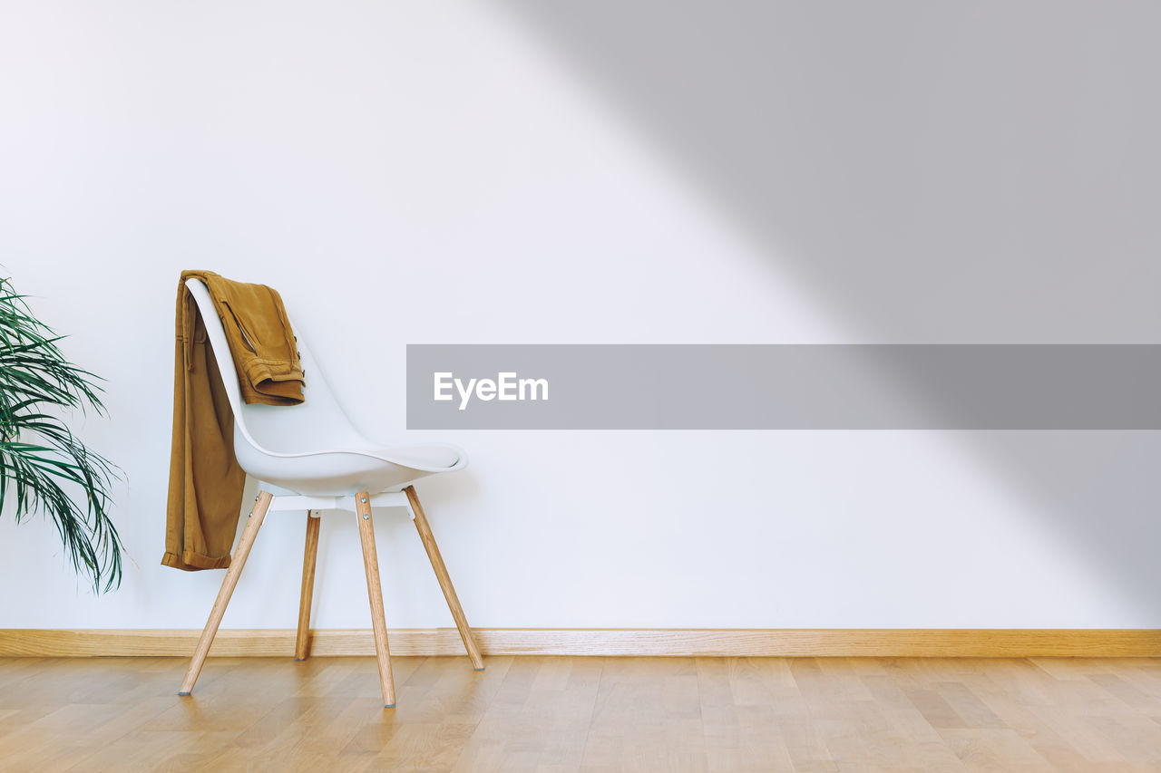 EMPTY CHAIRS AND TABLES ON HARDWOOD FLOOR AGAINST WALL