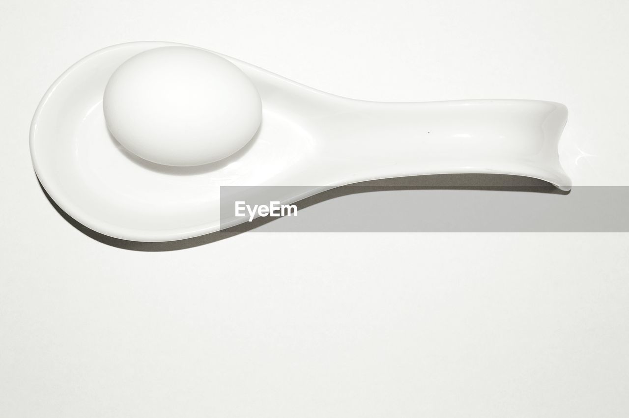 Close-up of egg in spoon over white background