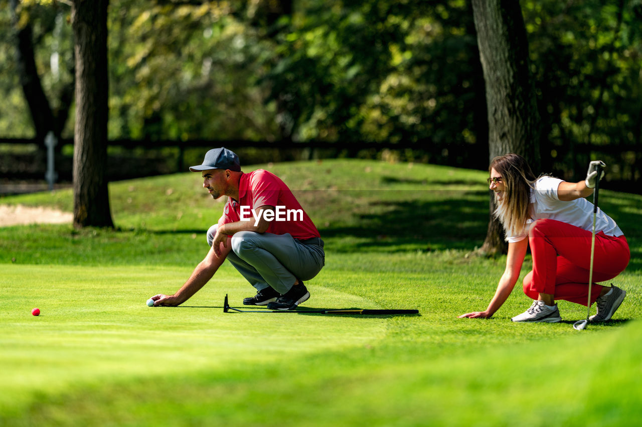 Young couple on a golf course, reading green