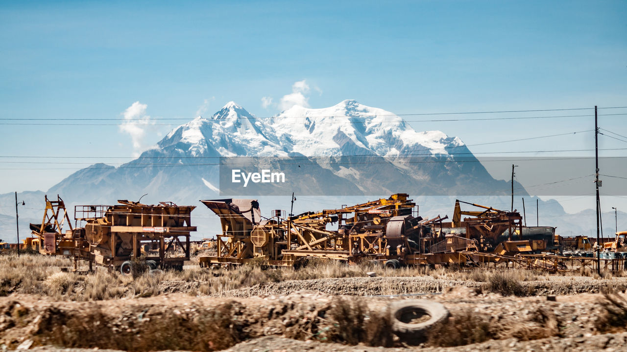 Abandoned construction machinery against on field against snowcapped mountain