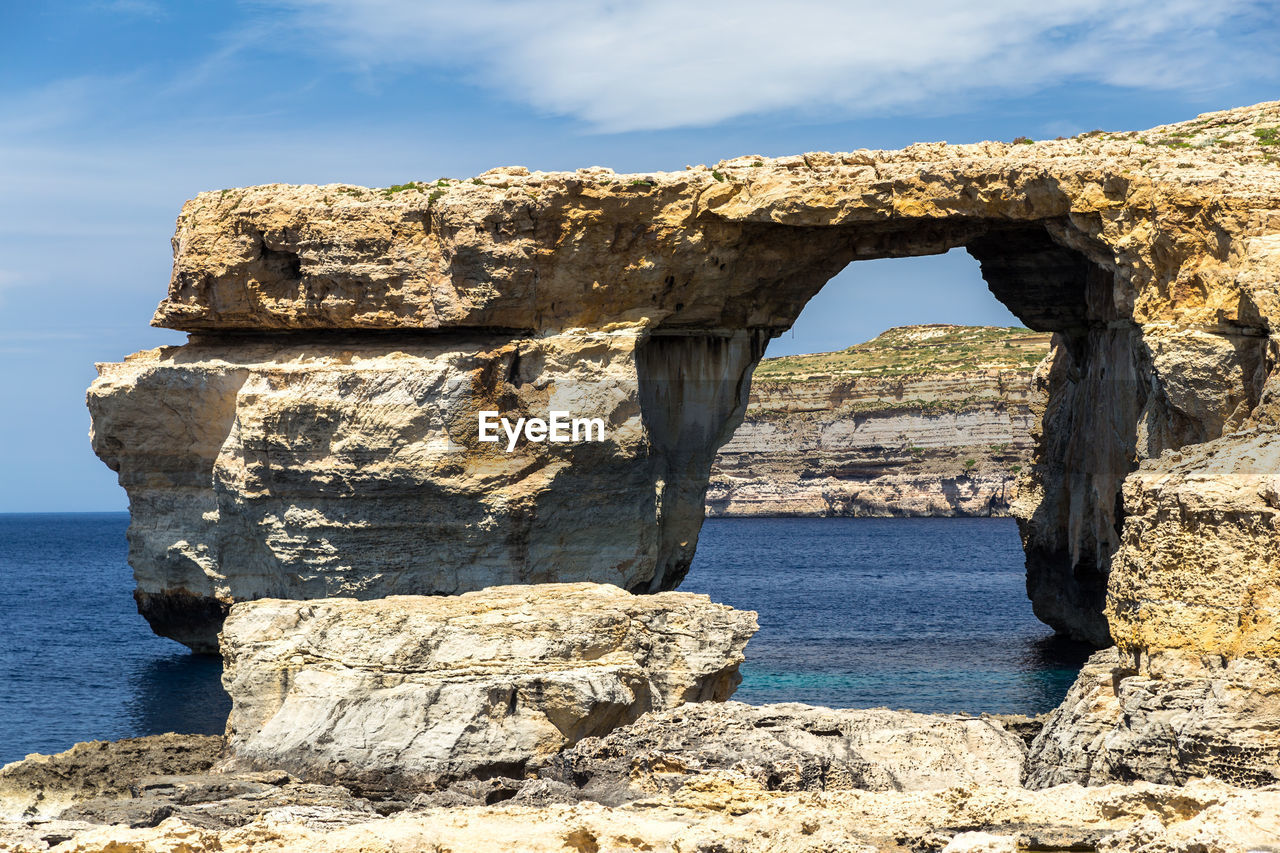 Rock formation by sea against sky