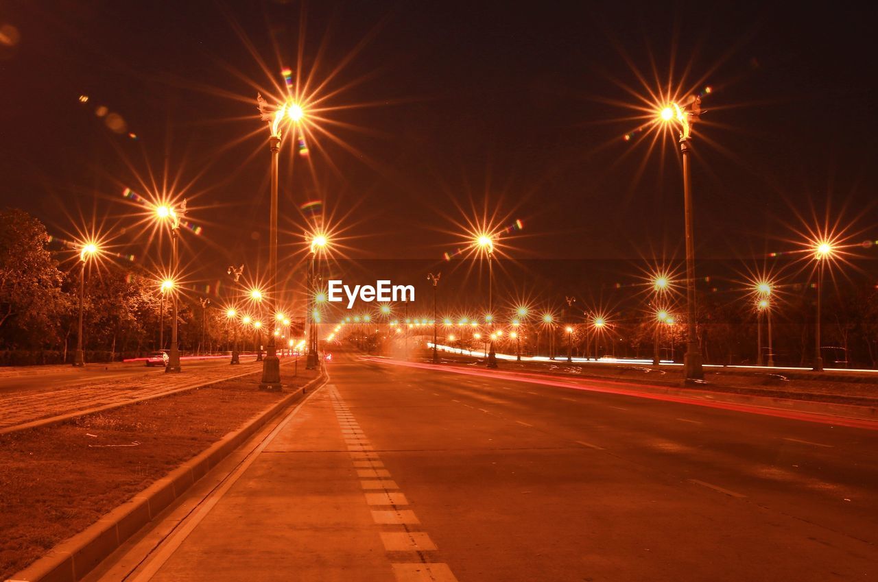 LIGHT TRAILS ON ROAD IN CITY AT NIGHT