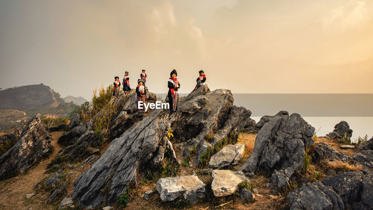 PEOPLE ON ROCK FORMATION AGAINST SKY