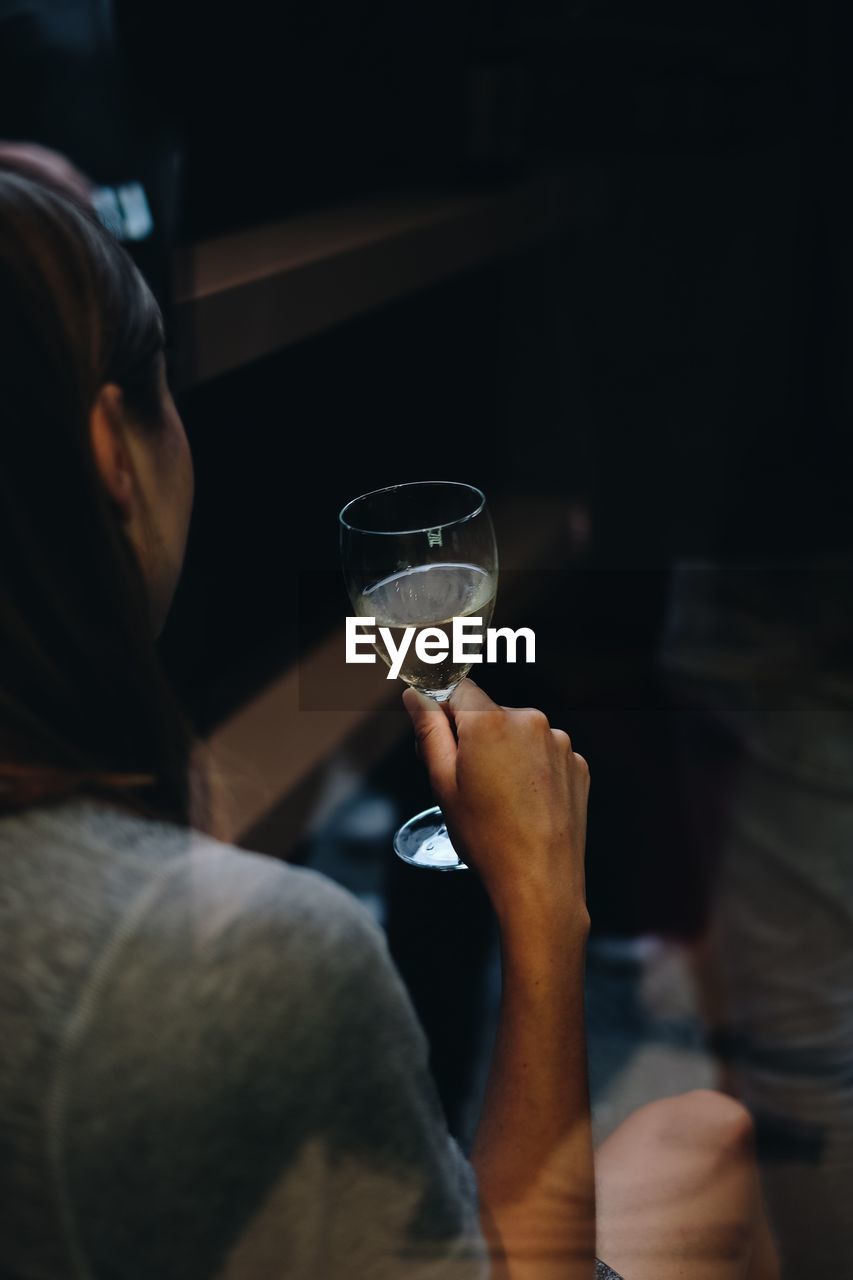 Close-up of woman holding wineglass seen through window