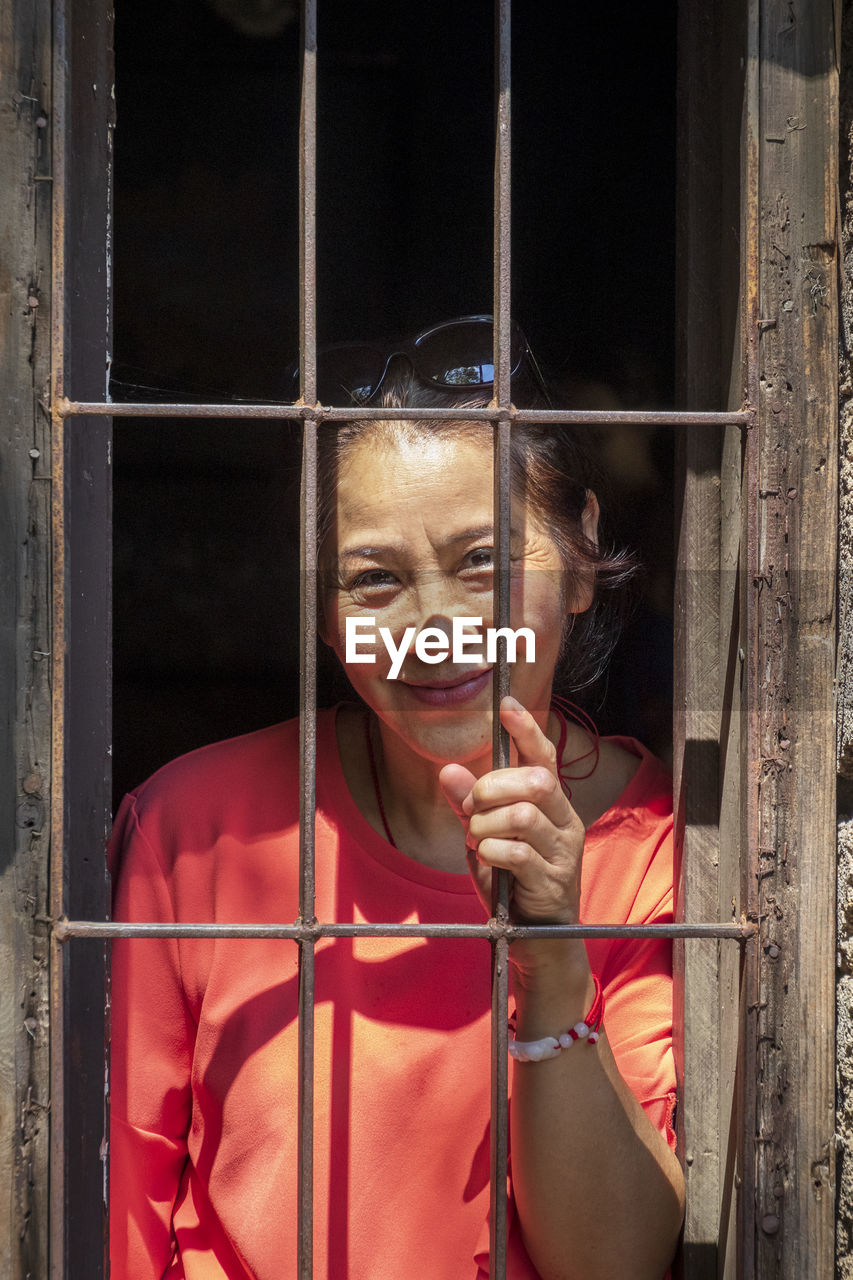 Portrait of smiling senior woman looking through window