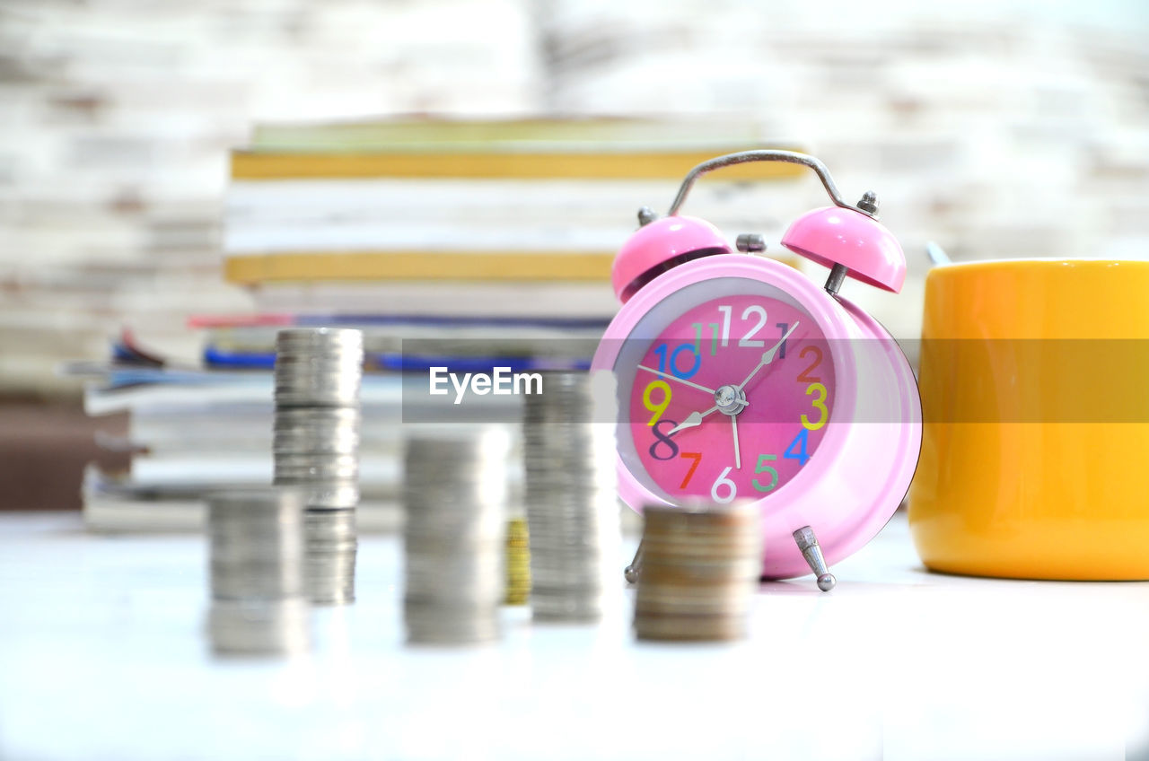 Stacked coins and alarm clock on desk