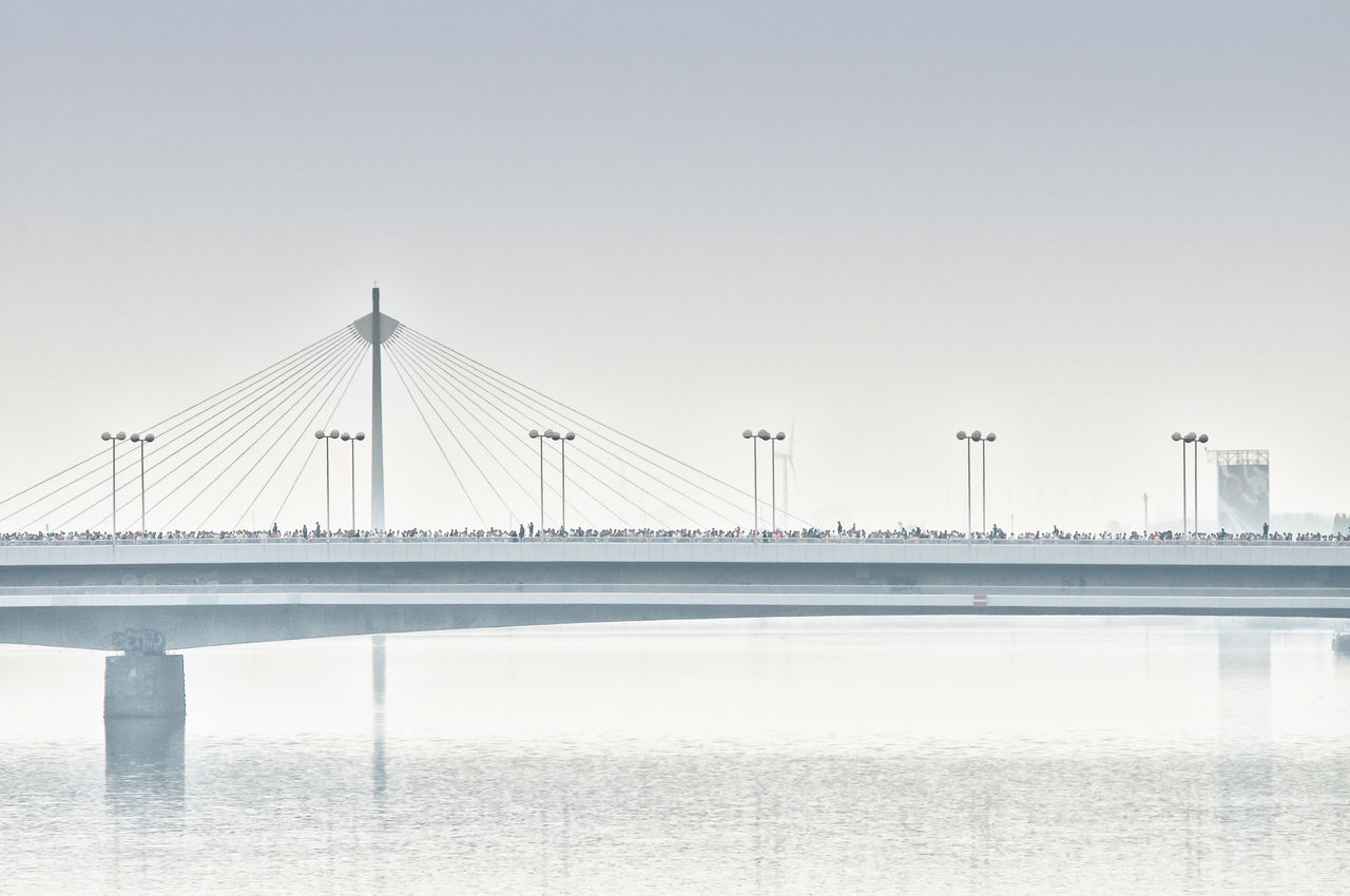 Marathon run on bridge over river against sky