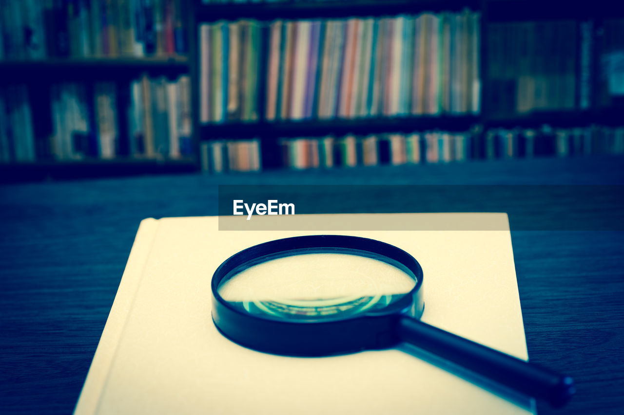 Magnifying glass with book on table