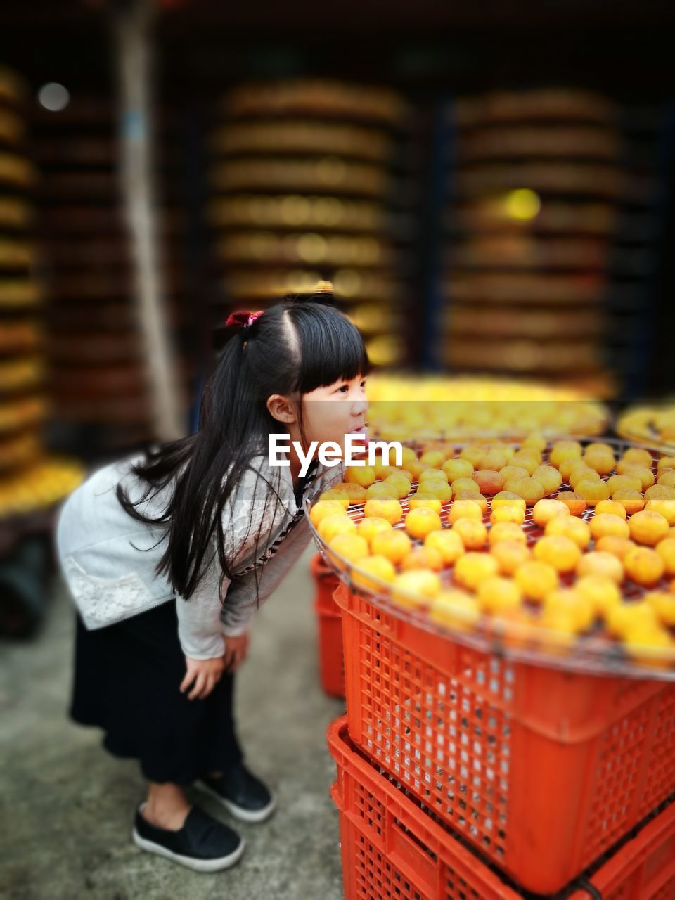 Girl sticking out tongue by sweet food in container on crates