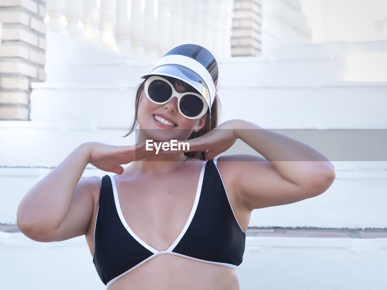 portrait of young woman wearing sunglasses while standing against white wall