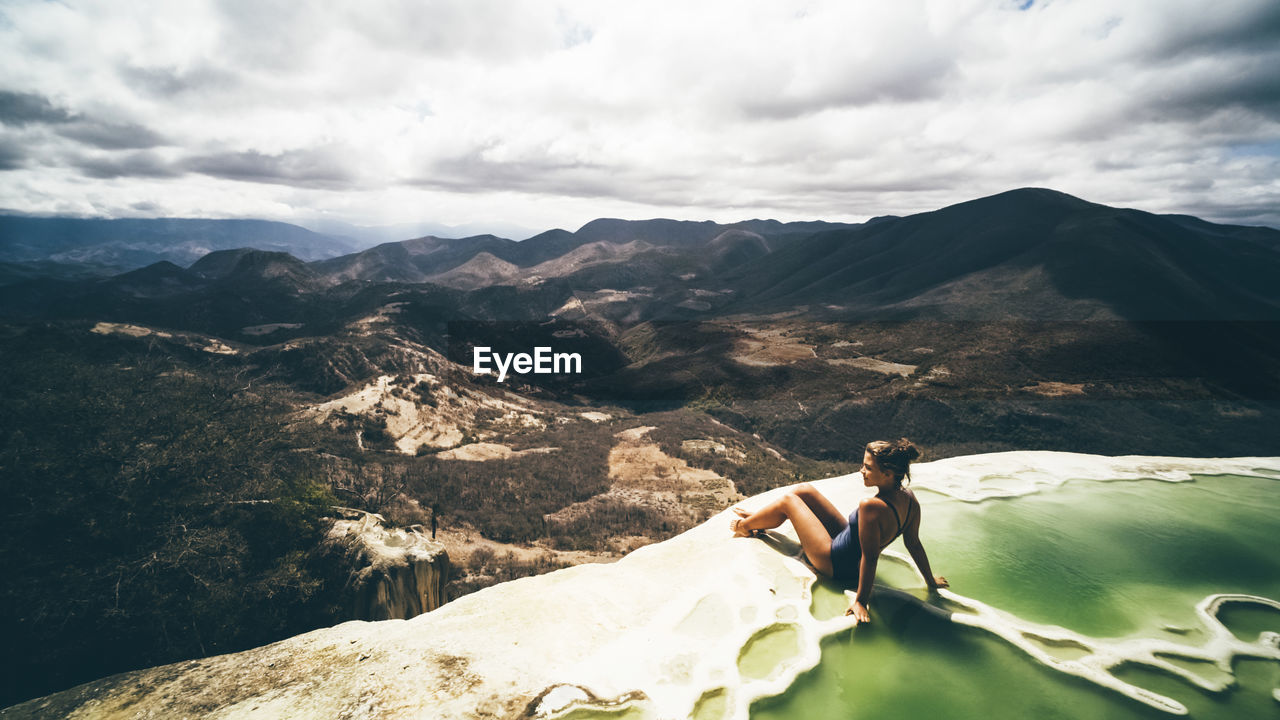 Panoram view with young girl sitting on the brink of mineral pool, mexico hierve el agua