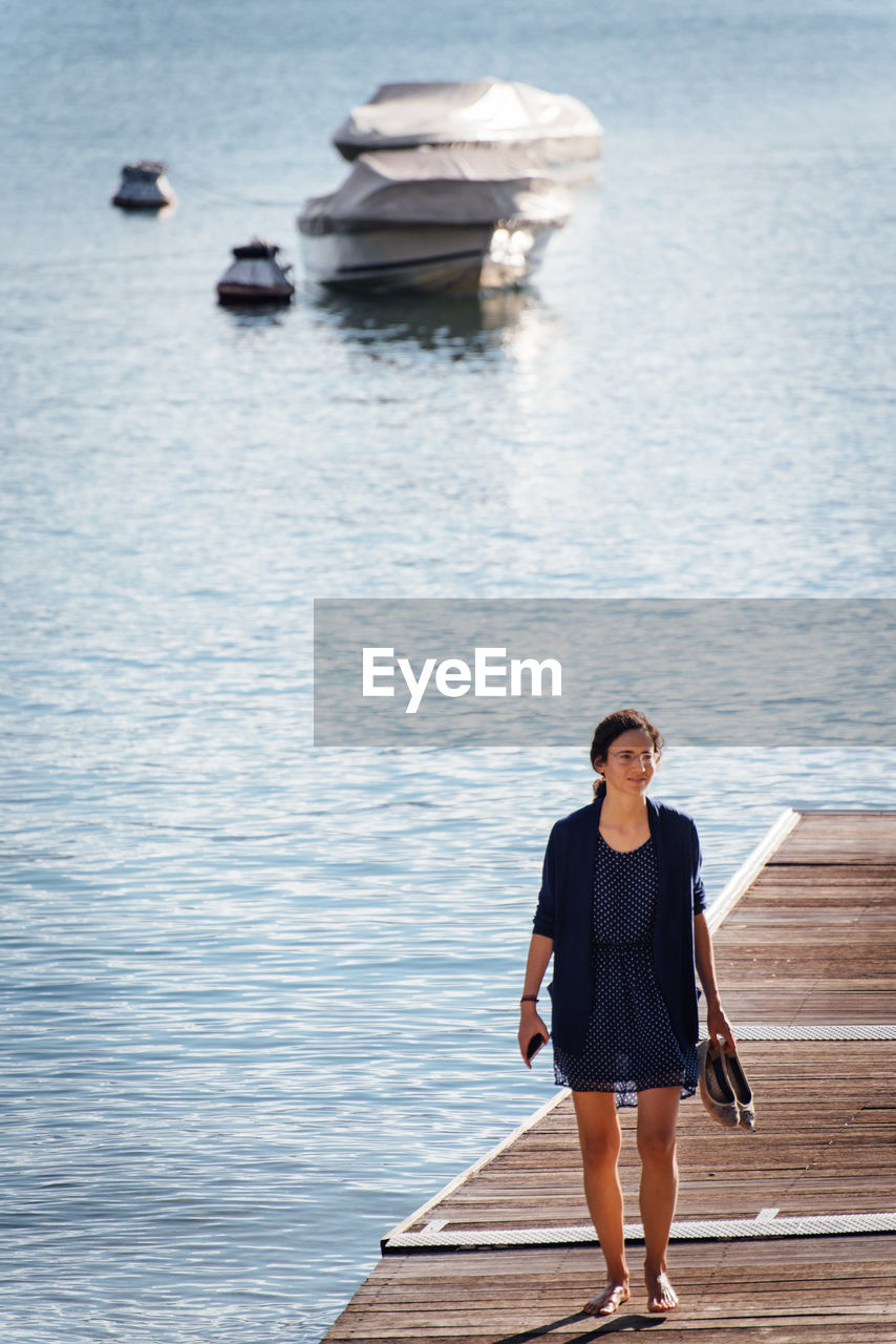 FULL LENGTH OF WOMAN STANDING ON JETTY